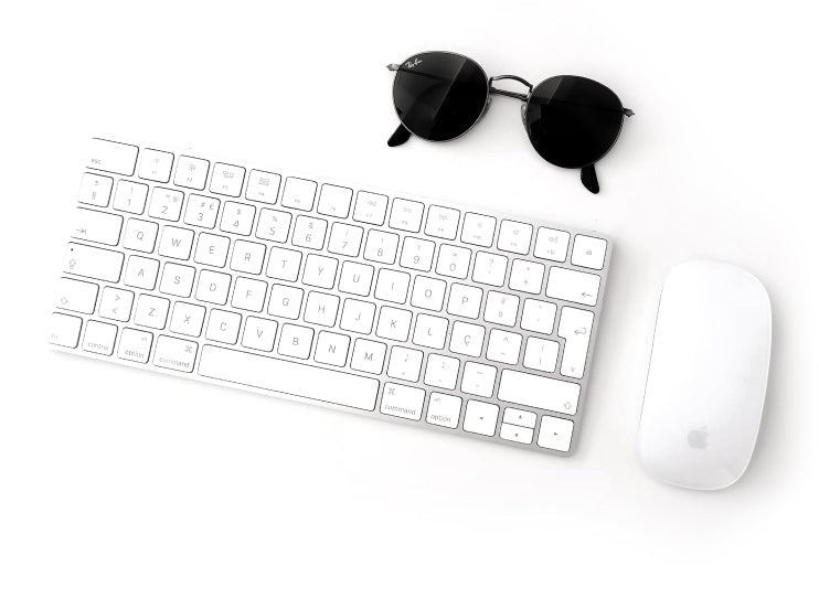 A white keyboard next to a white mouse and a pair of round, black sunglasses, all on a white surface.