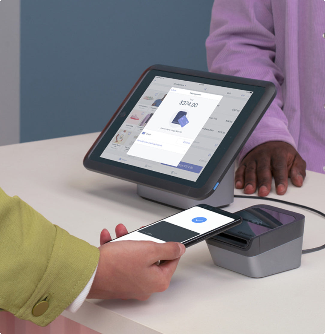 Customer completing a contactless payment using a smartphone at a Shopify POS system with the screen displaying a transaction in progress.